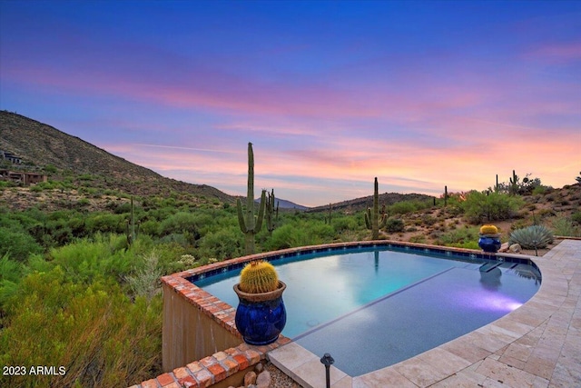 pool at dusk featuring a mountain view