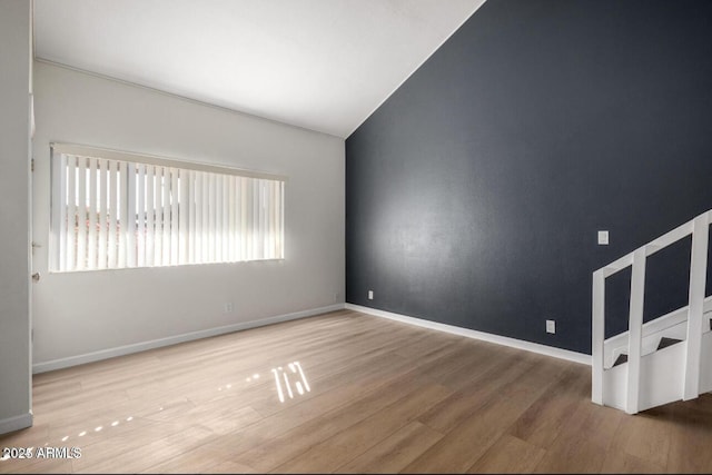 empty room with vaulted ceiling and hardwood / wood-style floors