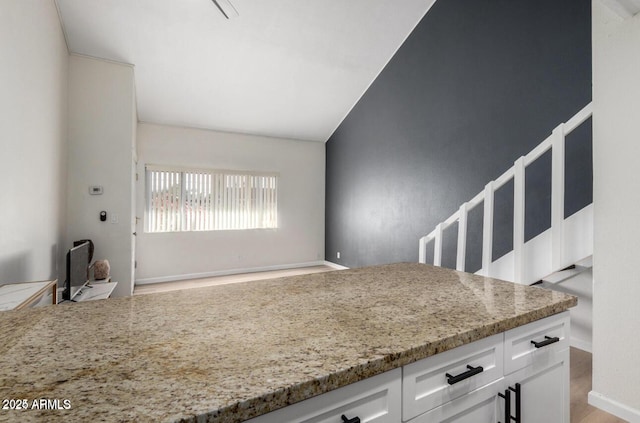 kitchen with light wood-type flooring, white cabinets, and light stone counters