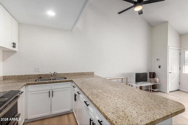 kitchen with ceiling fan, kitchen peninsula, sink, white cabinets, and light stone counters