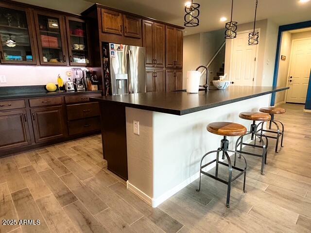 3871 E Harrison St, Gilbert, AZ 85295 - kitchen featuring dark countertops, stainless steel fridge, light wood-style floors, and a kitchen breakfast bar
