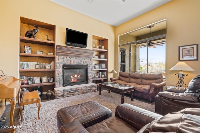 living room featuring built in shelves, ceiling fan, and a fireplace