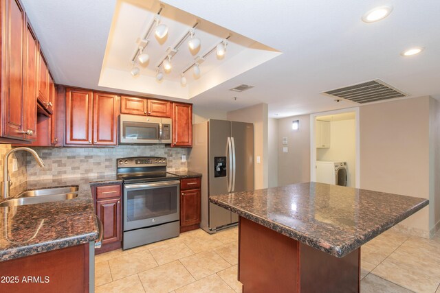 7970 E Camelback Rd Unit 604, Scottsdale, AZ 85251 - kitchen featuring stainless steel appliances, a sink, a tray ceiling, decorative backsplash, and light tile patterned flooring