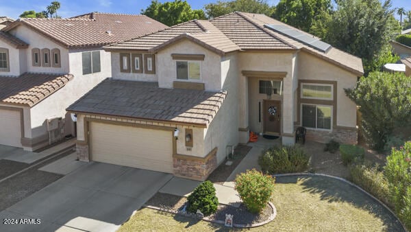 view of front of house with a garage, concrete driveway, a tiled roof, and roof mounted solar panels