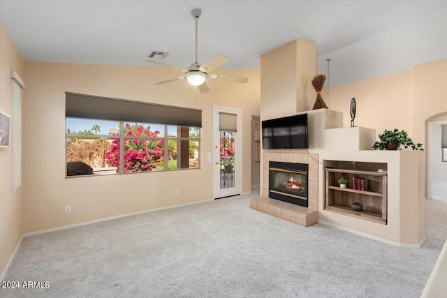 living room featuring a tiled fireplace, light carpet, vaulted ceiling, and ceiling fan