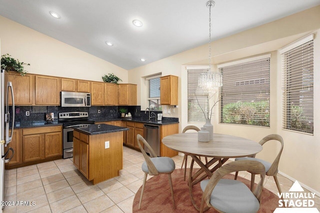 kitchen featuring lofted ceiling, appliances with stainless steel finishes, sink, pendant lighting, and a center island