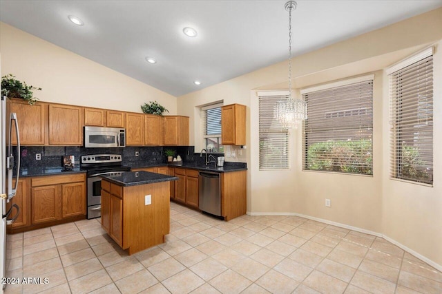 kitchen with a kitchen island, vaulted ceiling, stainless steel appliances, sink, and decorative light fixtures