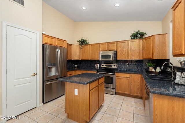 kitchen featuring light tile patterned floors, appliances with stainless steel finishes, backsplash, a kitchen island, and sink