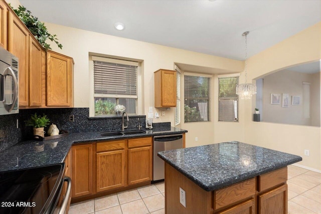 kitchen with sink, appliances with stainless steel finishes, decorative light fixtures, and a wealth of natural light