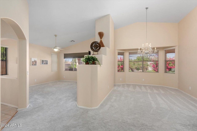 carpeted spare room with high vaulted ceiling and ceiling fan with notable chandelier