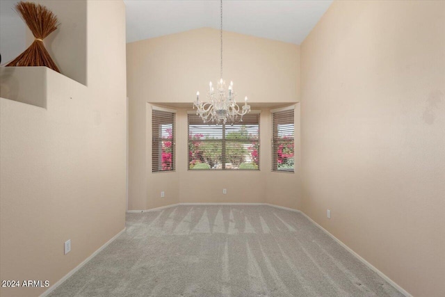 spare room featuring a chandelier, light carpet, and high vaulted ceiling