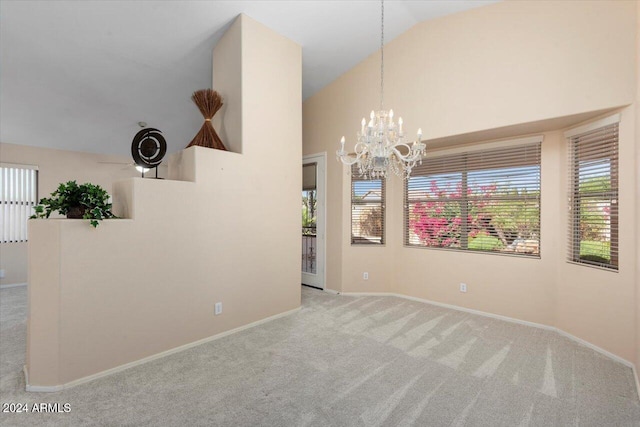 carpeted empty room featuring vaulted ceiling and a chandelier