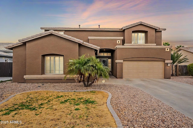 mediterranean / spanish-style house featuring stucco siding, a garage, concrete driveway, and fence