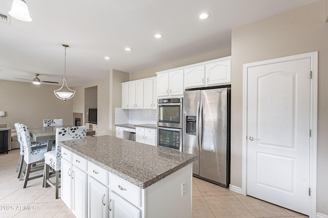 kitchen featuring white cabinetry, stainless steel appliances, tasteful backsplash, a kitchen island, and decorative light fixtures