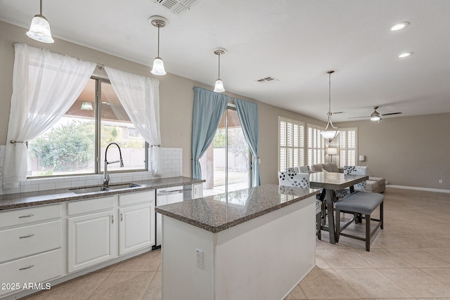 kitchen featuring visible vents, a sink, decorative backsplash, open floor plan, and a center island