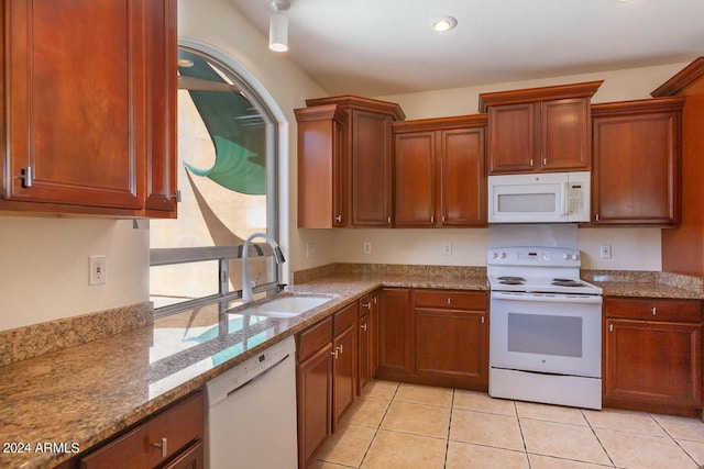 kitchen with light tile patterned floors, light stone counters, sink, and white appliances