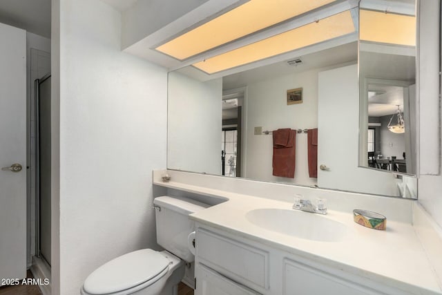 bathroom featuring vanity, a shower with door, and toilet