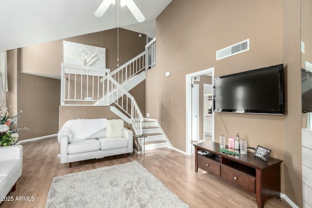 living room with a towering ceiling, wood-type flooring, and ceiling fan