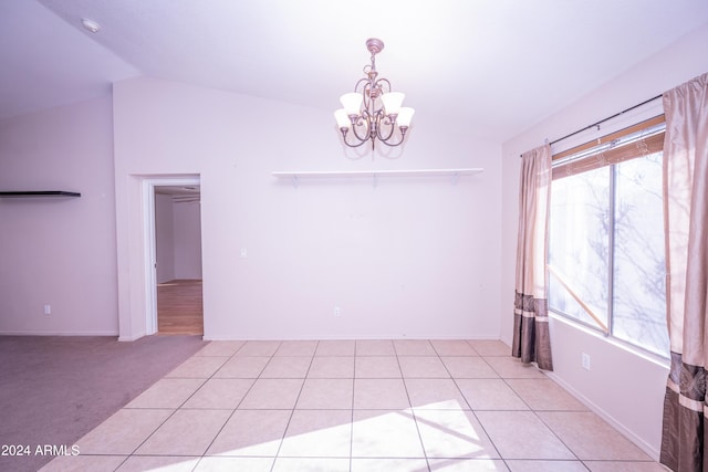 tiled empty room with plenty of natural light, vaulted ceiling, and an inviting chandelier