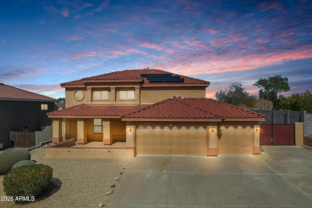 mediterranean / spanish-style home featuring an attached garage, stucco siding, concrete driveway, a tile roof, and roof mounted solar panels