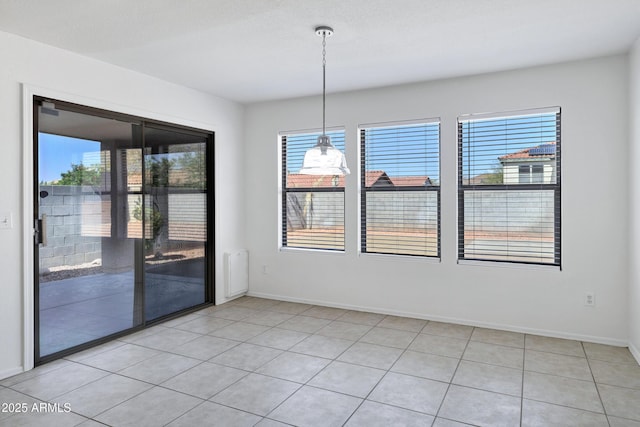 unfurnished dining area with plenty of natural light, light tile patterned flooring, and baseboards