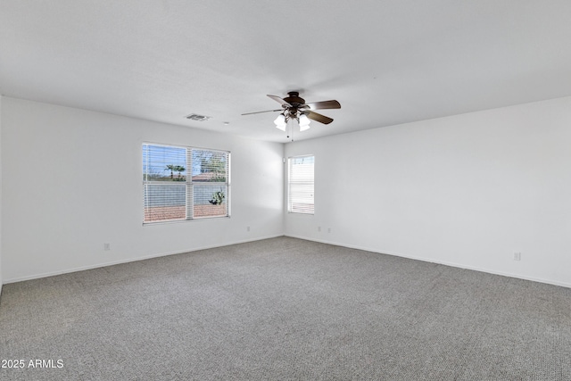 carpeted empty room with a ceiling fan, visible vents, and baseboards