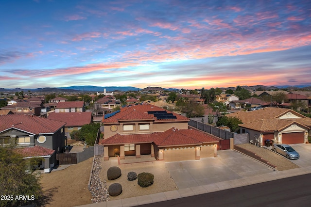 view of front of home with a mountain view, a residential view, a garage, solar panels, and a tiled roof