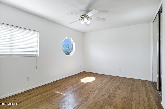 unfurnished bedroom featuring ceiling fan, a closet, baseboards, and wood finished floors