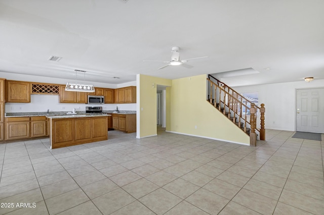 kitchen featuring visible vents, a kitchen island, light countertops, appliances with stainless steel finishes, and brown cabinets