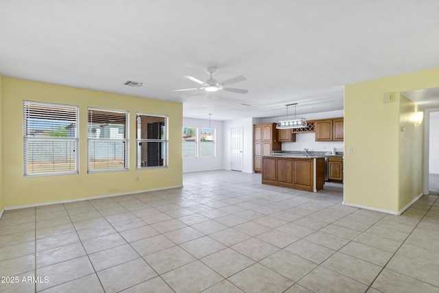 unfurnished living room with light tile patterned floors, baseboards, visible vents, a sink, and ceiling fan