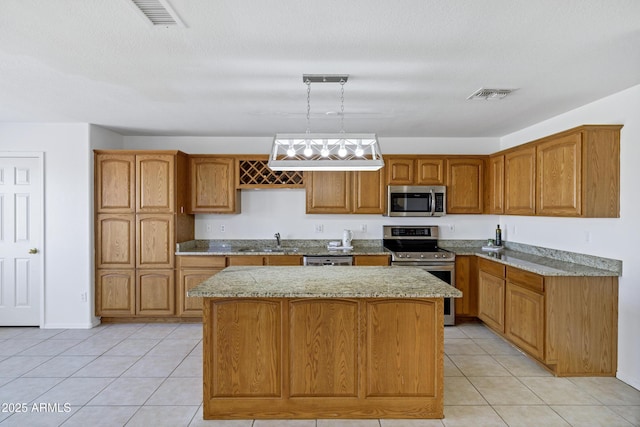 kitchen with visible vents, a kitchen island, light stone counters, stainless steel appliances, and a sink