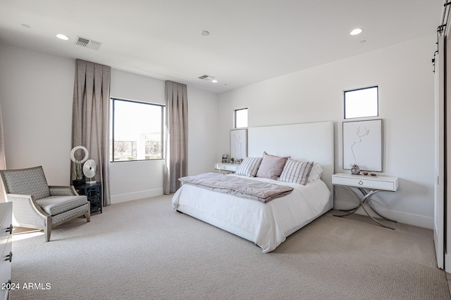 bedroom featuring a barn door and light colored carpet