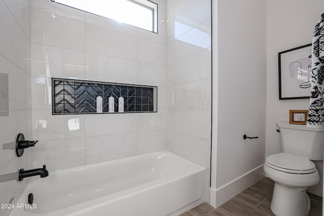 bathroom with tiled shower / bath combo, wood-type flooring, and toilet