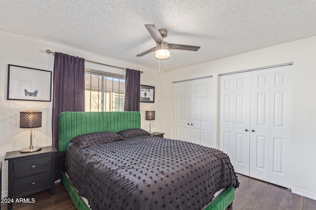 bedroom with a textured ceiling, dark hardwood / wood-style flooring, two closets, and ceiling fan