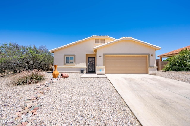 view of front facade featuring driveway, an attached garage, a tiled roof, and stucco siding