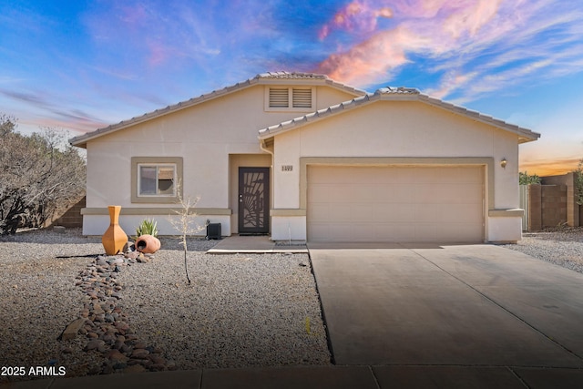 view of front of house featuring a garage, concrete driveway, a tile roof, and stucco siding