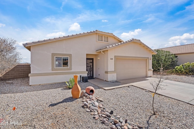 mediterranean / spanish house featuring driveway, a tiled roof, an attached garage, and stucco siding