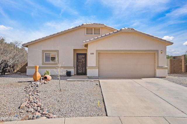 view of front facade with driveway, an attached garage, a tile roof, and stucco siding