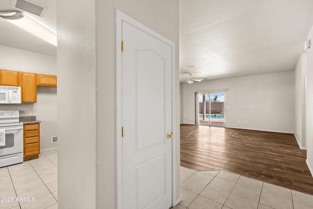 kitchen with light tile patterned floors, white appliances, open floor plan, and visible vents