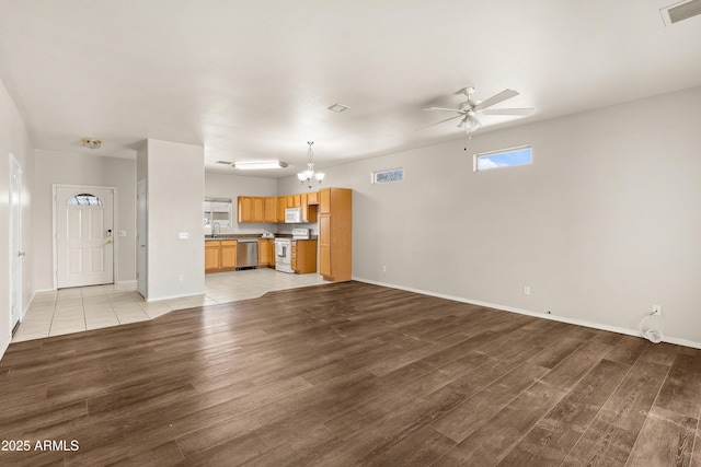 unfurnished living room featuring light wood-style floors, visible vents, a sink, and ceiling fan with notable chandelier