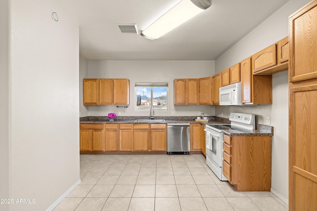 kitchen with visible vents, light tile patterned flooring, a sink, white appliances, and baseboards