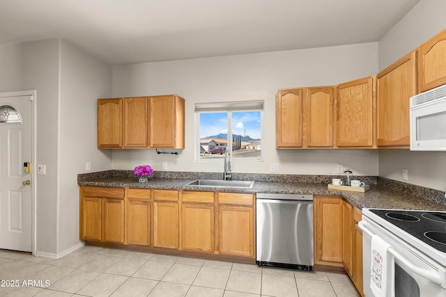 kitchen with dark countertops, white appliances, light tile patterned floors, and a sink