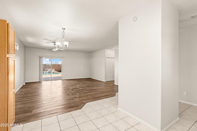 empty room with light tile patterned floors, baseboards, and a notable chandelier