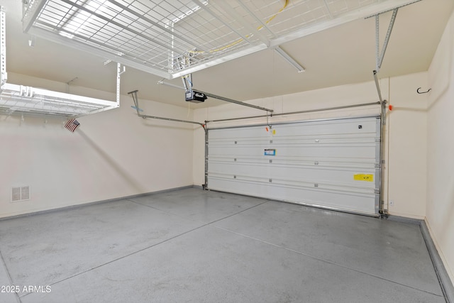 garage with a garage door opener, visible vents, and baseboards