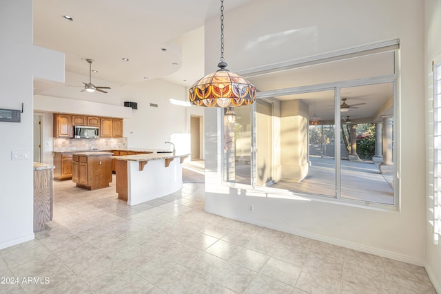 kitchen with a breakfast bar, a kitchen island, ceiling fan, and tasteful backsplash