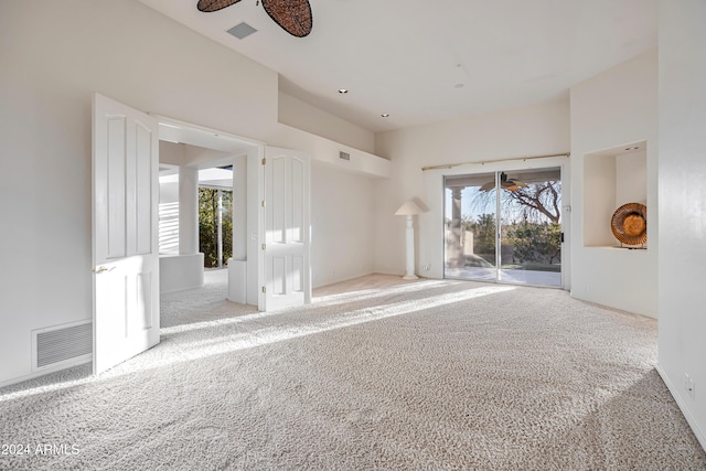 carpeted empty room featuring ceiling fan and a high ceiling