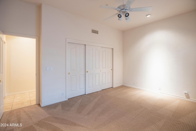 unfurnished bedroom featuring ceiling fan, light carpet, and a closet