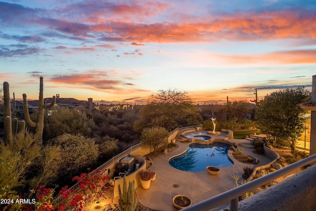 pool at dusk featuring an in ground hot tub and a patio