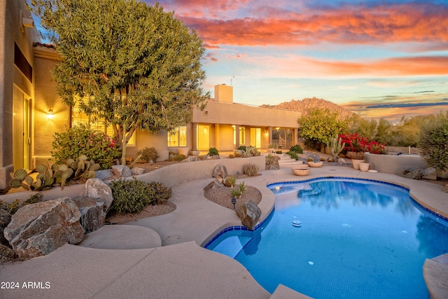 pool at dusk with a patio area