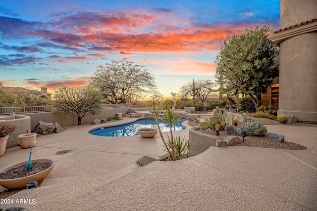 pool at dusk featuring a patio area